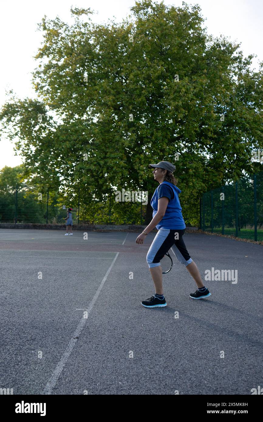 Donna che gioca a tennis sul campo di quartiere Foto Stock