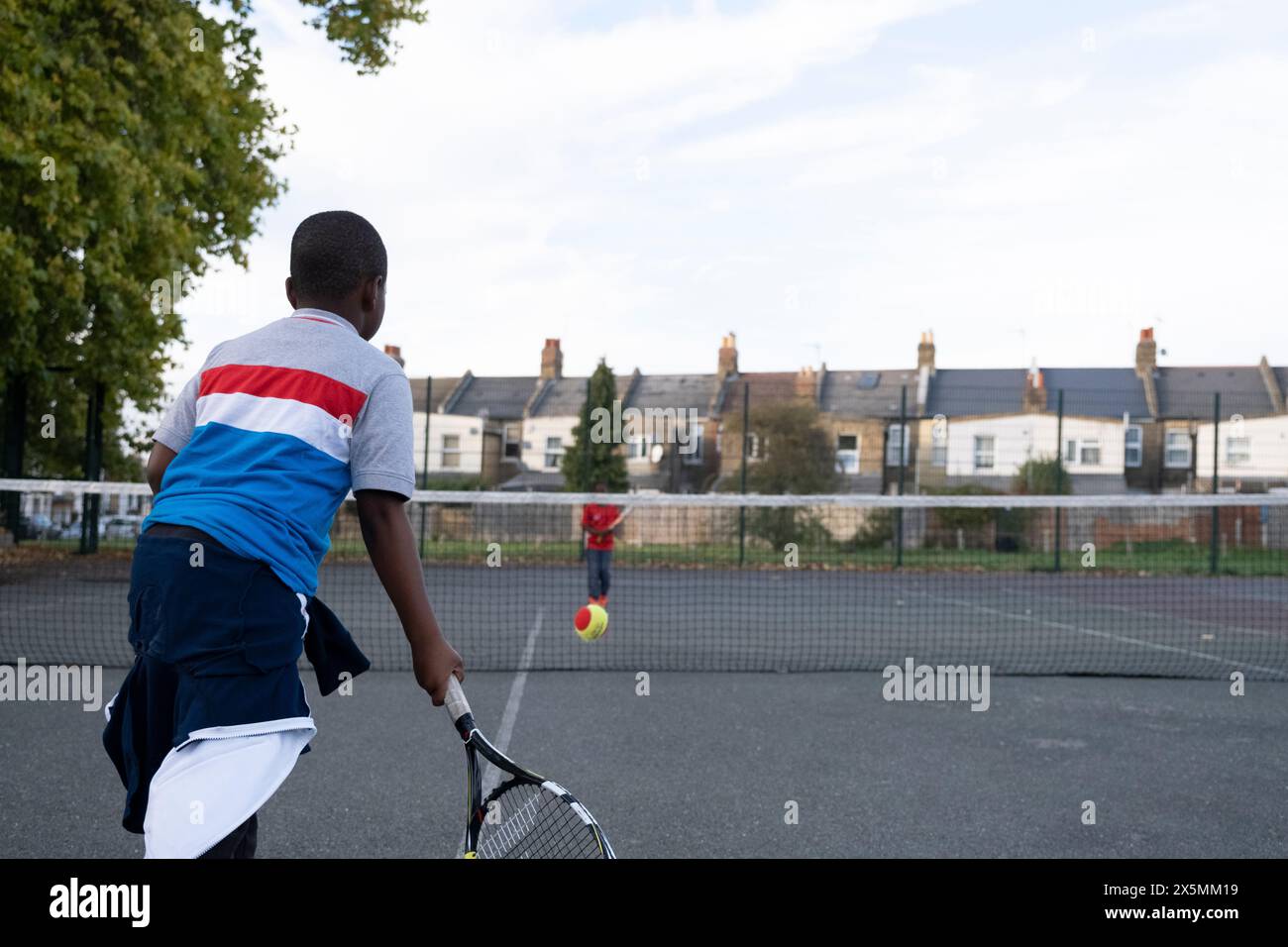 I bambini giocano a tennis sul campo di quartiere Foto Stock