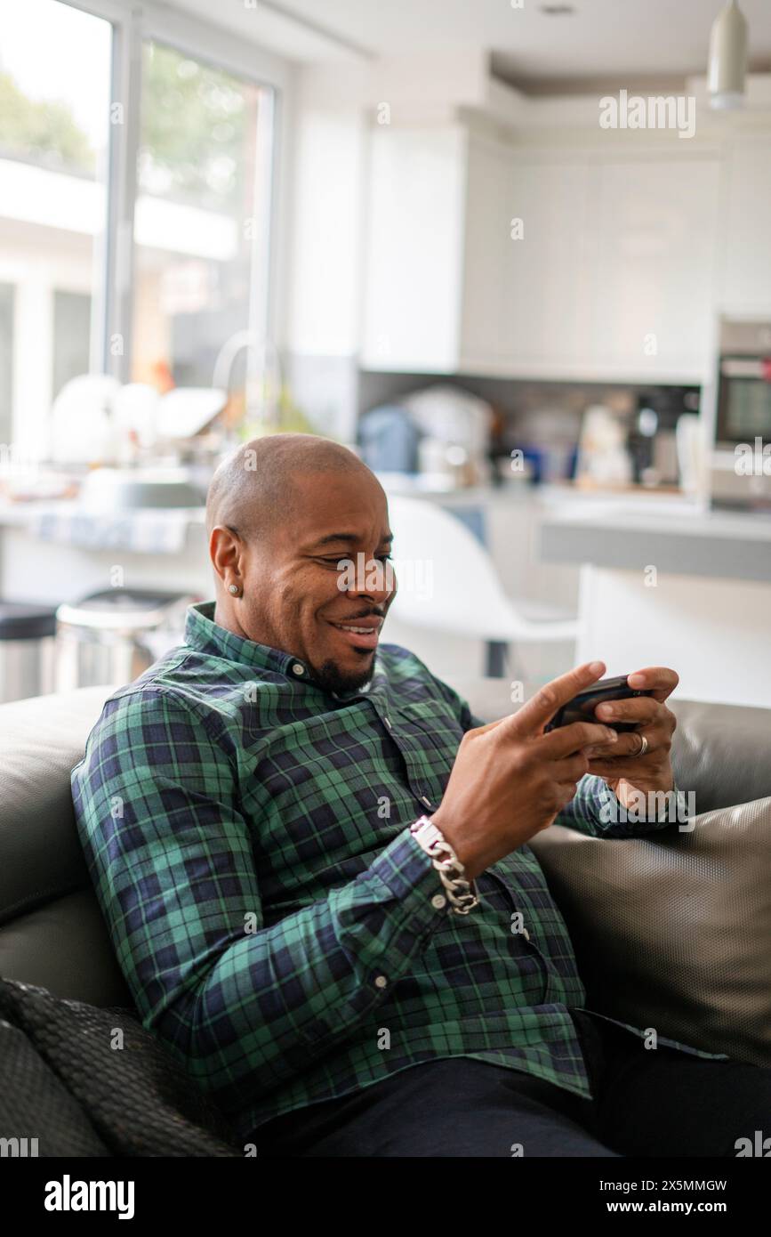 Uomo maturo che usa lo smartphone a casa Foto Stock