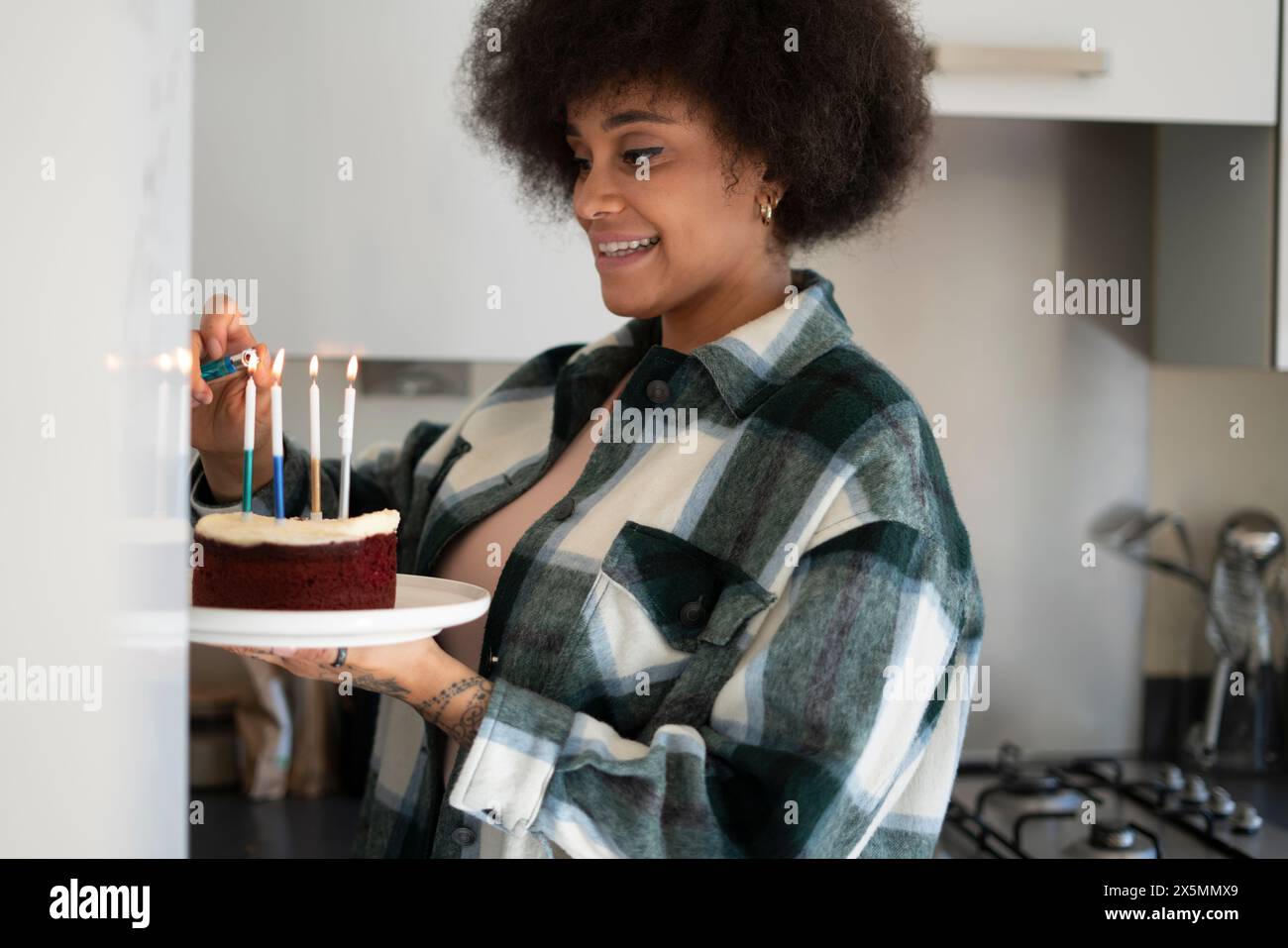 Donna che accende le candele sulla torta di compleanno Foto Stock