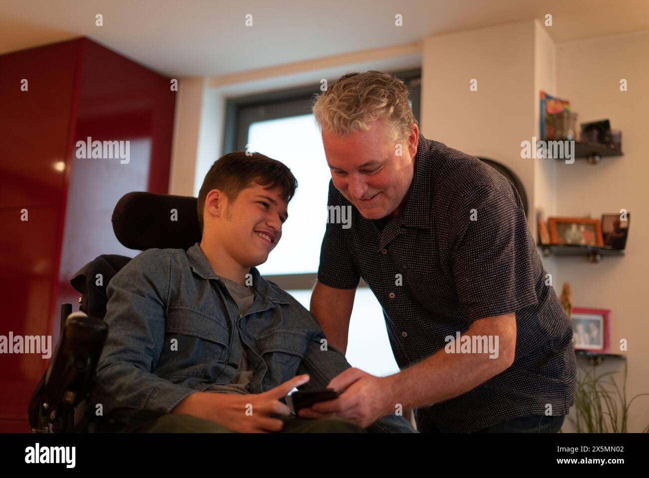 Padre che passa del tempo con un figlio disabile a casa Foto Stock