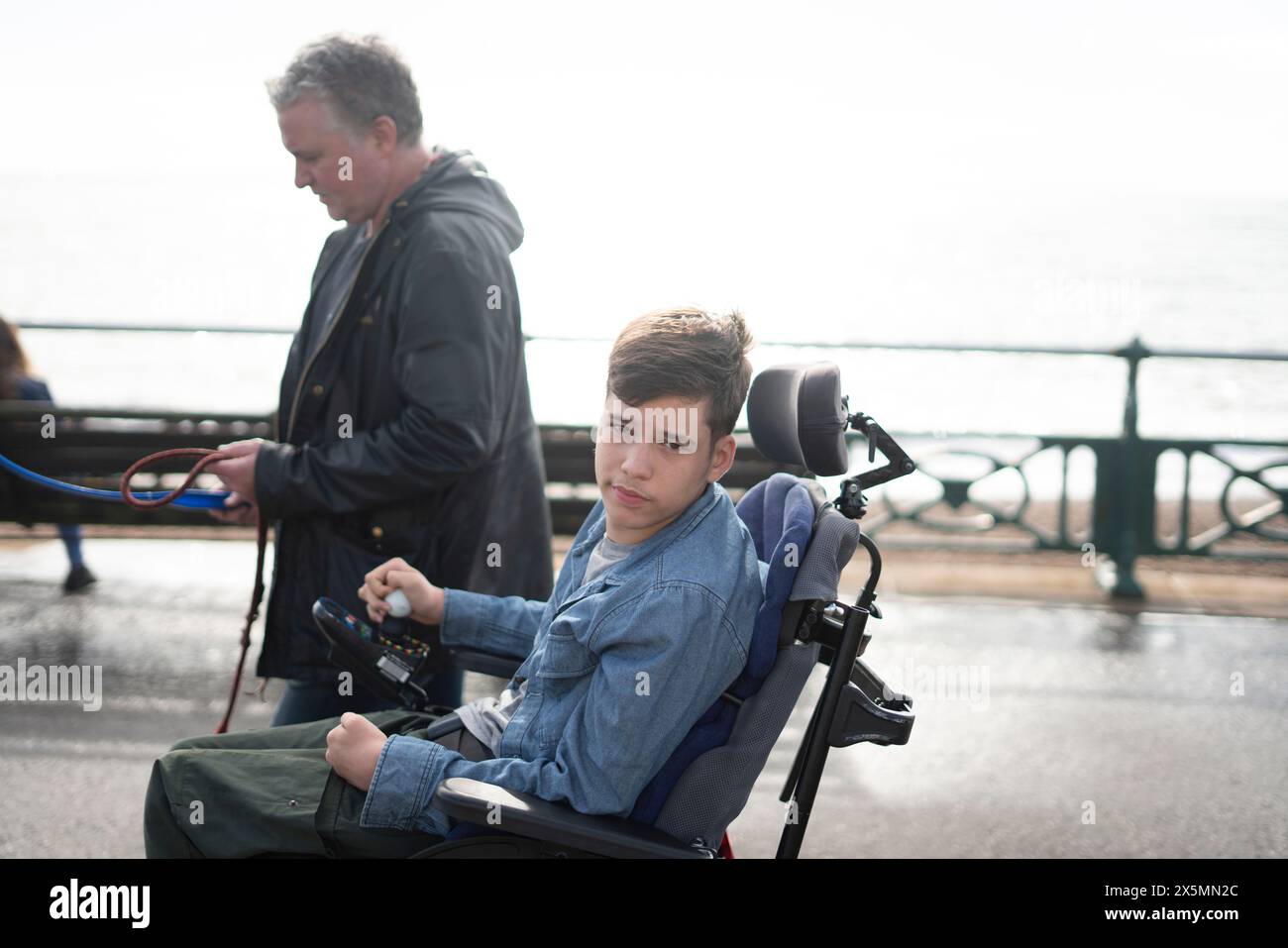 Padre e figlio disabile che passeggiano sul lungomare Foto Stock