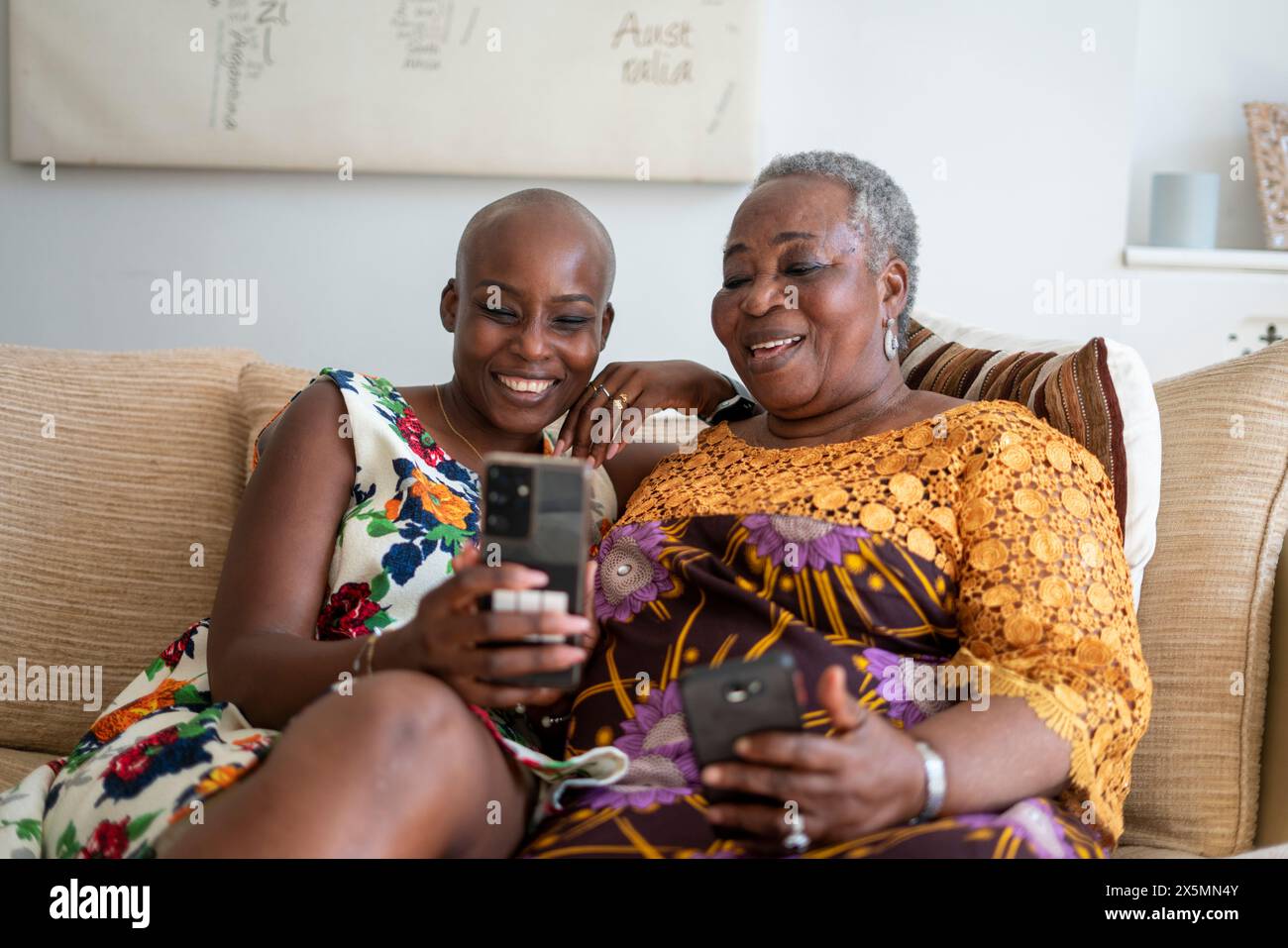 Donna sorridente con madre che sta videochiamando sullo smartphone a casa Foto Stock