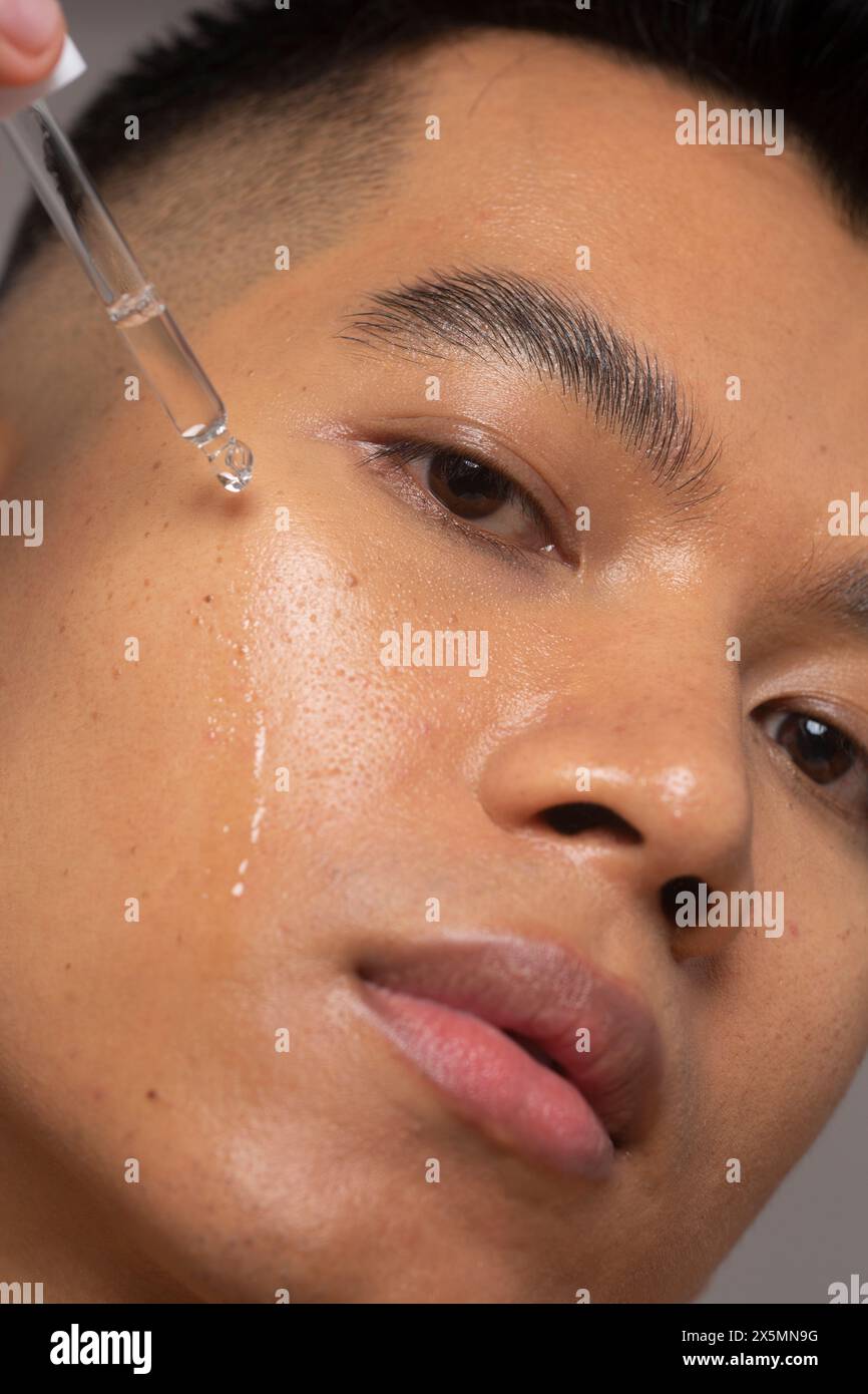 Primo piano della persona che applica il siero sul viso Foto Stock