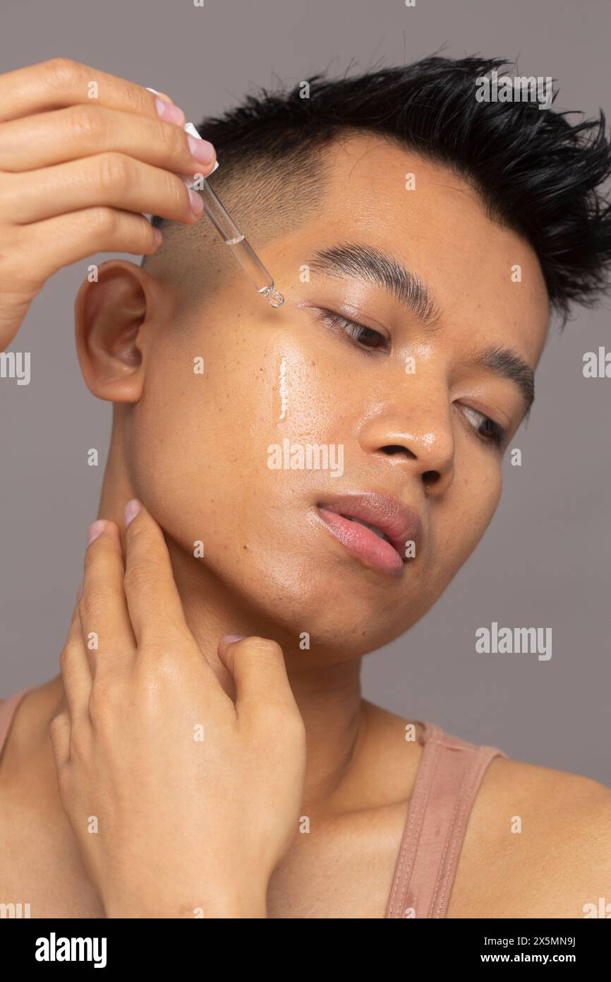 Primo piano della persona che applica il siero sul viso Foto Stock