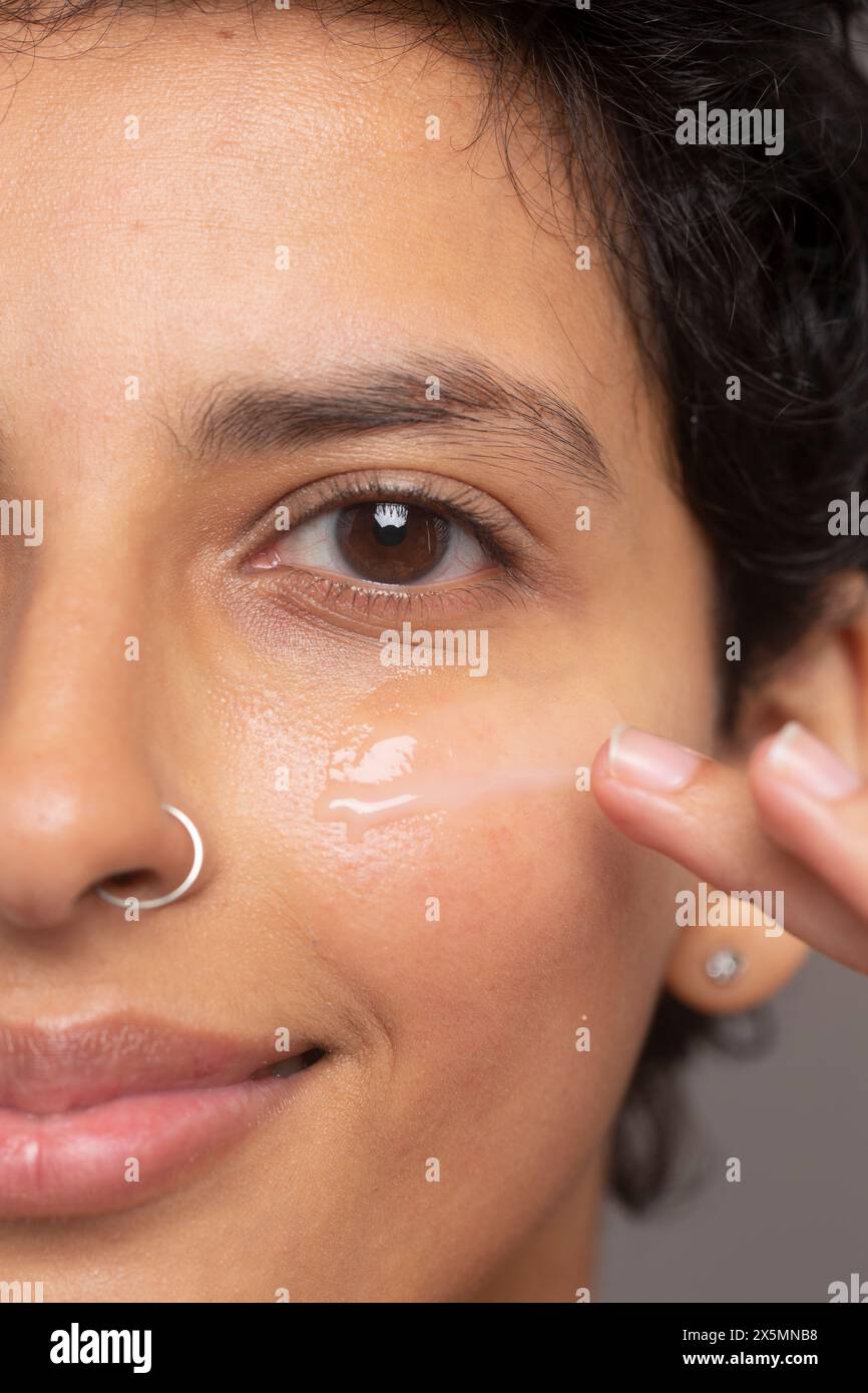 Primo piano di una donna sorridente che applica l'idratante sul viso Foto Stock