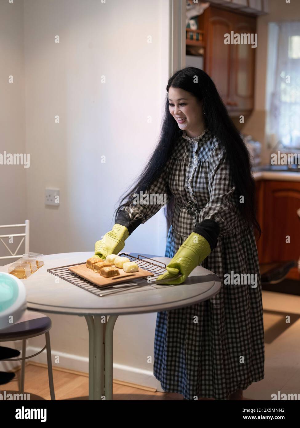 Donna che mette teglia da forno con torte lunari sul tavolo Foto Stock