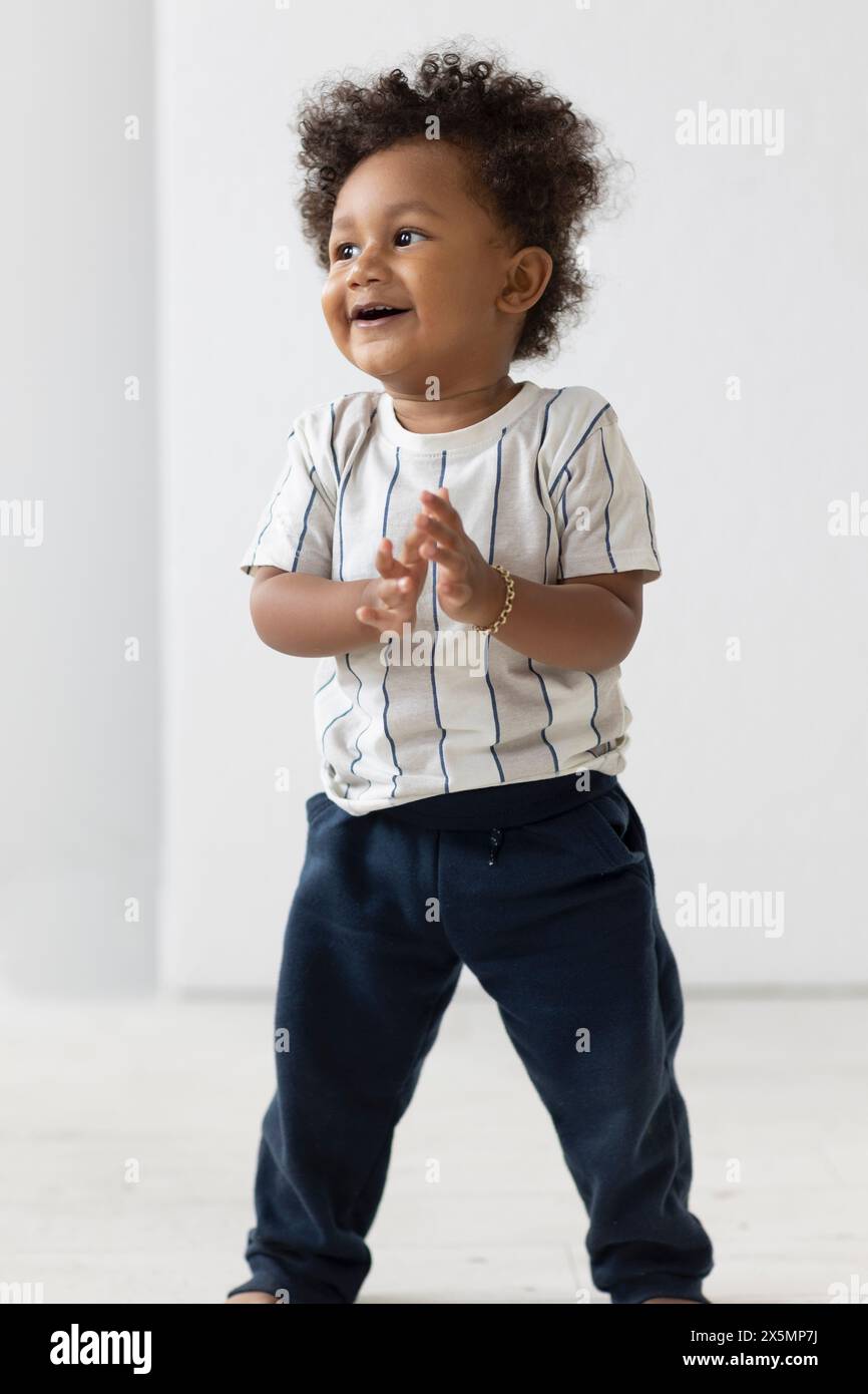 Bambino in piedi e che batte le mani Foto Stock