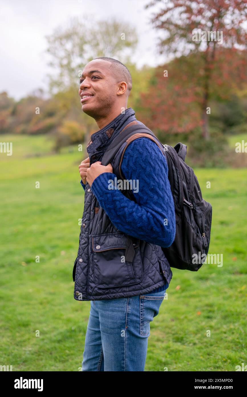 Uomo sorridente con zaino nel prato Foto Stock