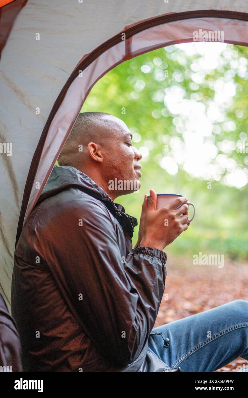 Uomo che si gode una bevanda calda in tenda Foto Stock