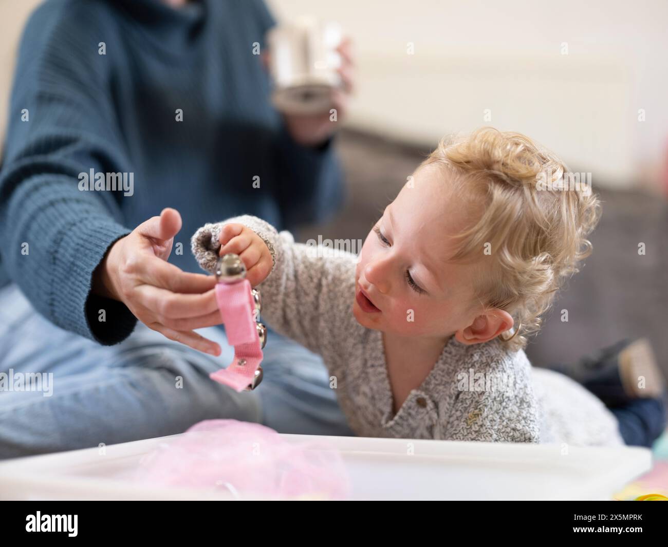 Mamma che appende il giocattolo al figlio Foto Stock