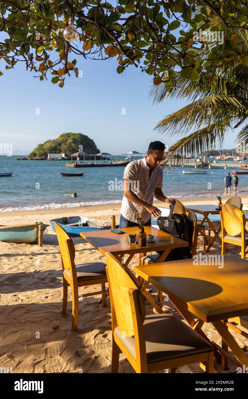 Uomo con zaino al bar sulla spiaggia Foto Stock