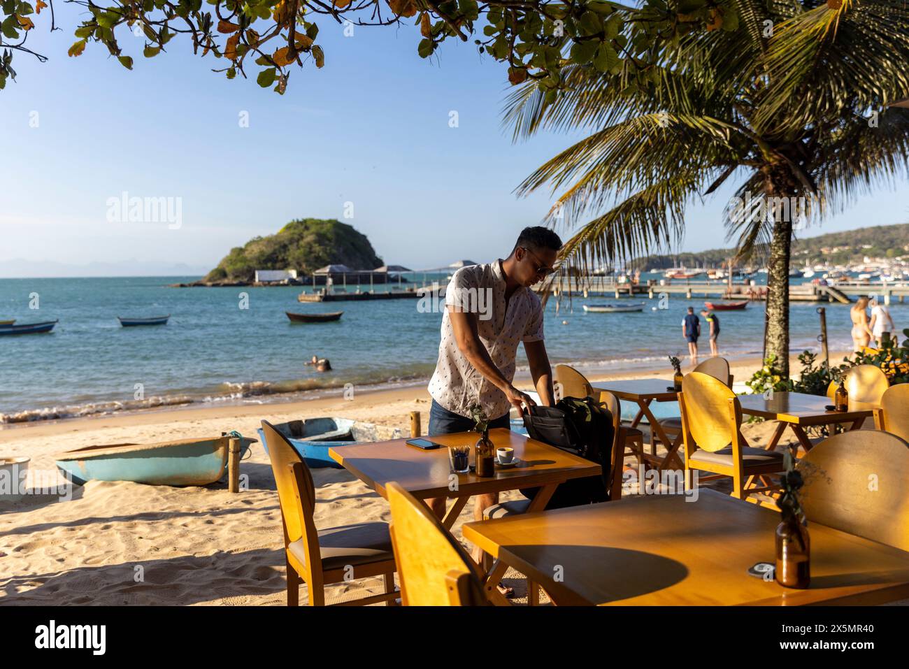 Uomo con zaino al bar sulla spiaggia Foto Stock