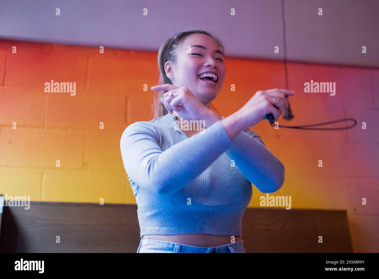 Donna sorridente che balla mentre gioca in un videogame al pub Foto Stock