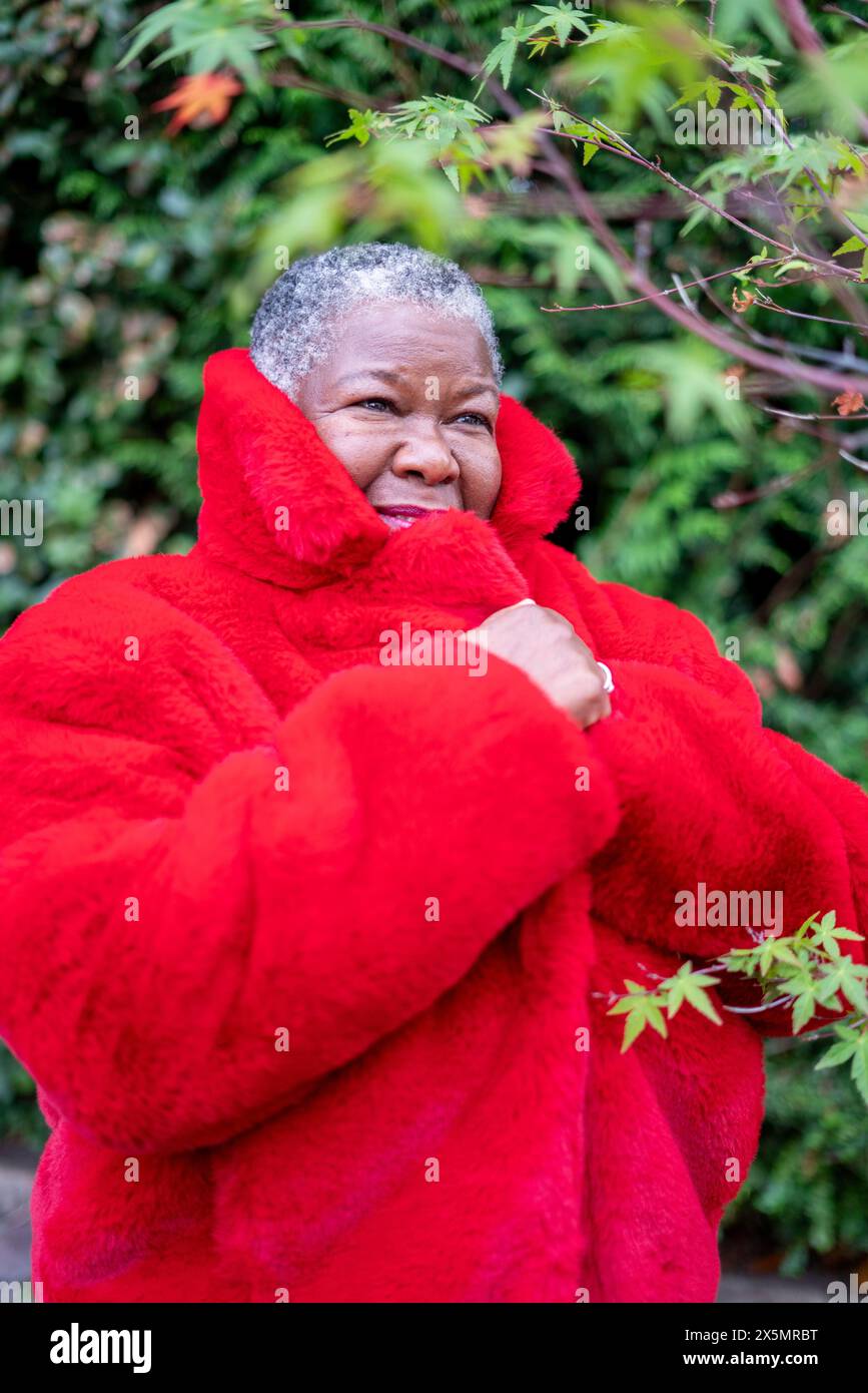Ritratto di una donna anziana che indossa un cappotto di pelliccia rossa Foto Stock