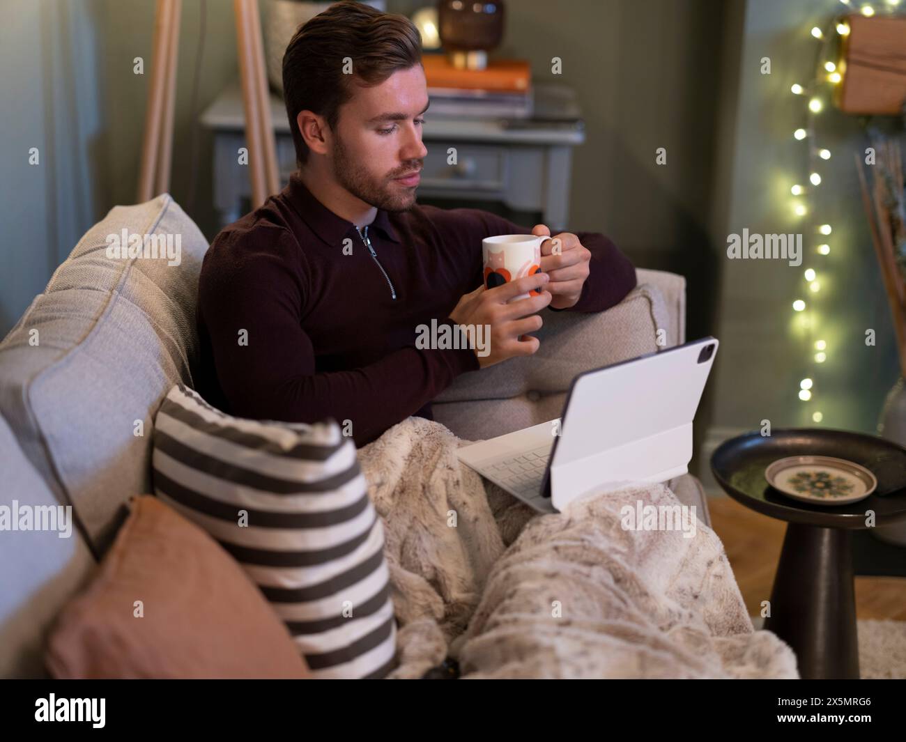 Giovane uomo che si rilassa sul divano con un tablet digitale Foto Stock