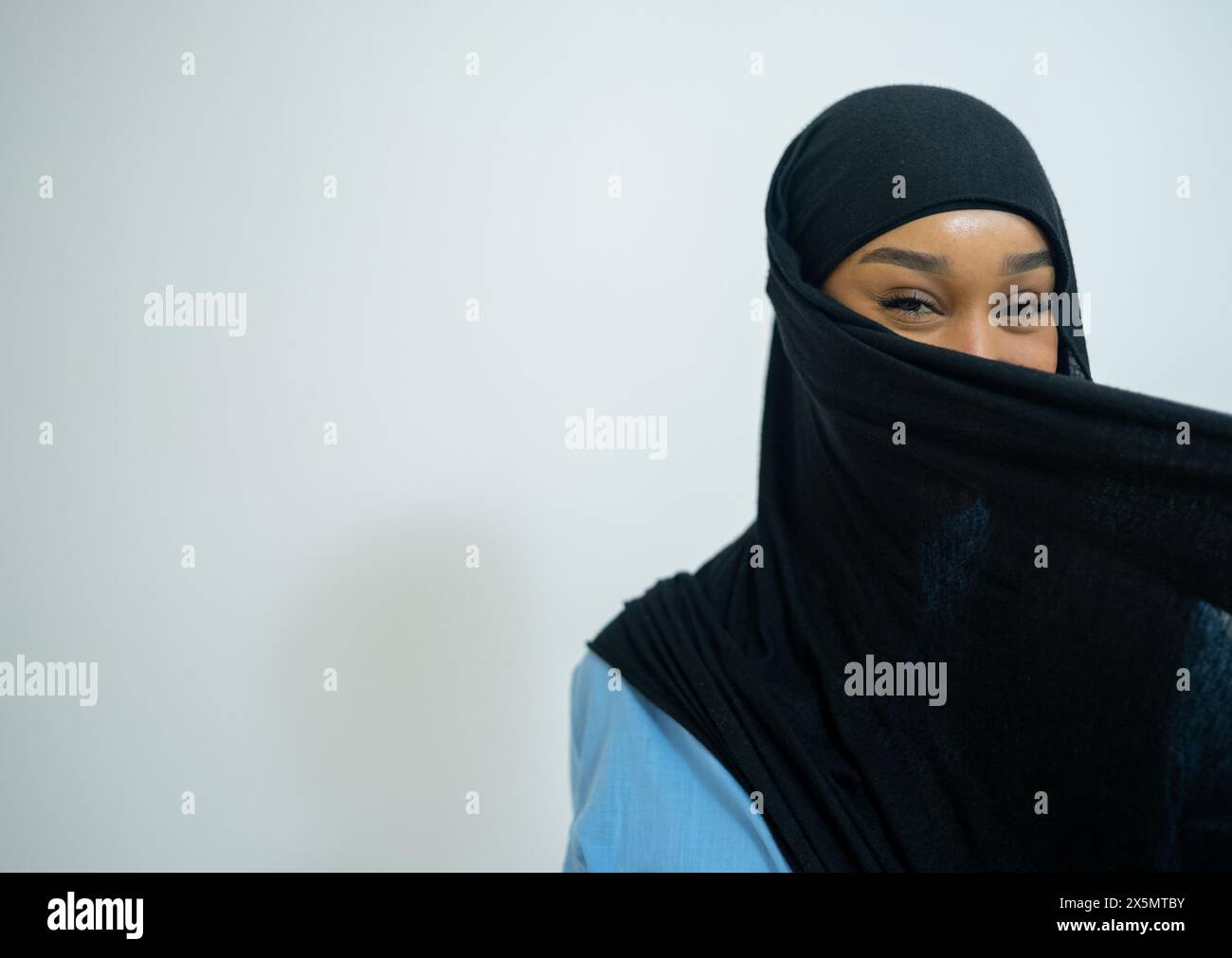 Ritratto di una giovane donna che copre il viso con hijab su sfondo bianco Foto Stock