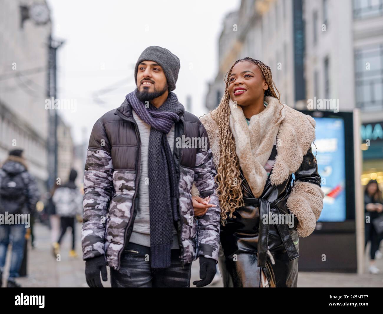 Giovane coppia sorridente che cammina in città Foto Stock