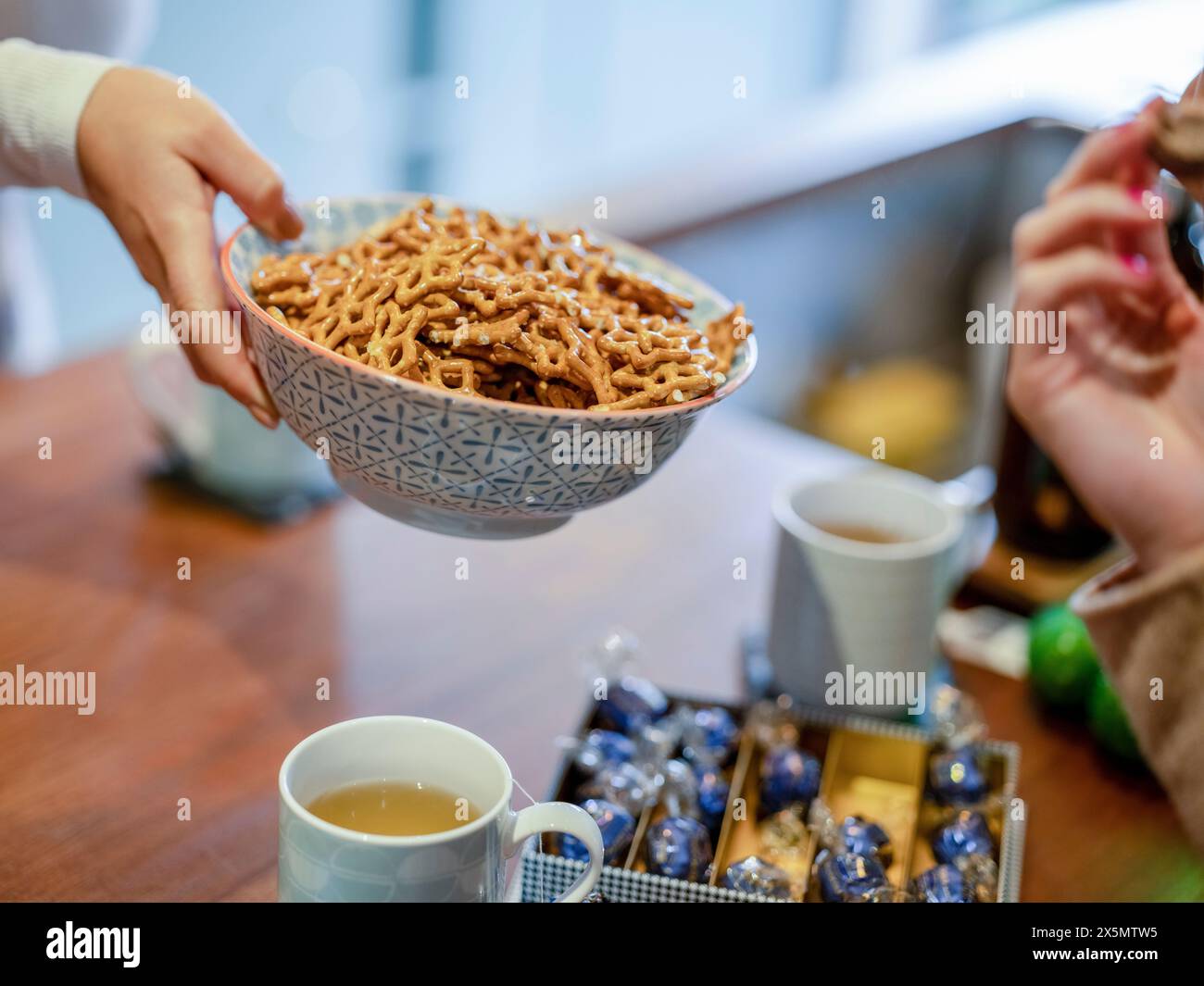 Amici che mangiano pretzel in cucina Foto Stock