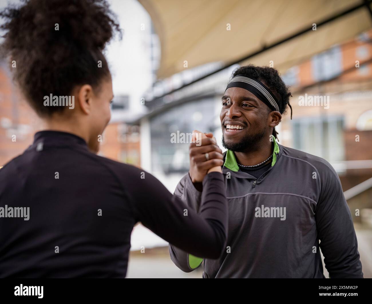 Uomo e donna sorridenti in abbigliamento sportivo braccio di lotta all'aperto Foto Stock