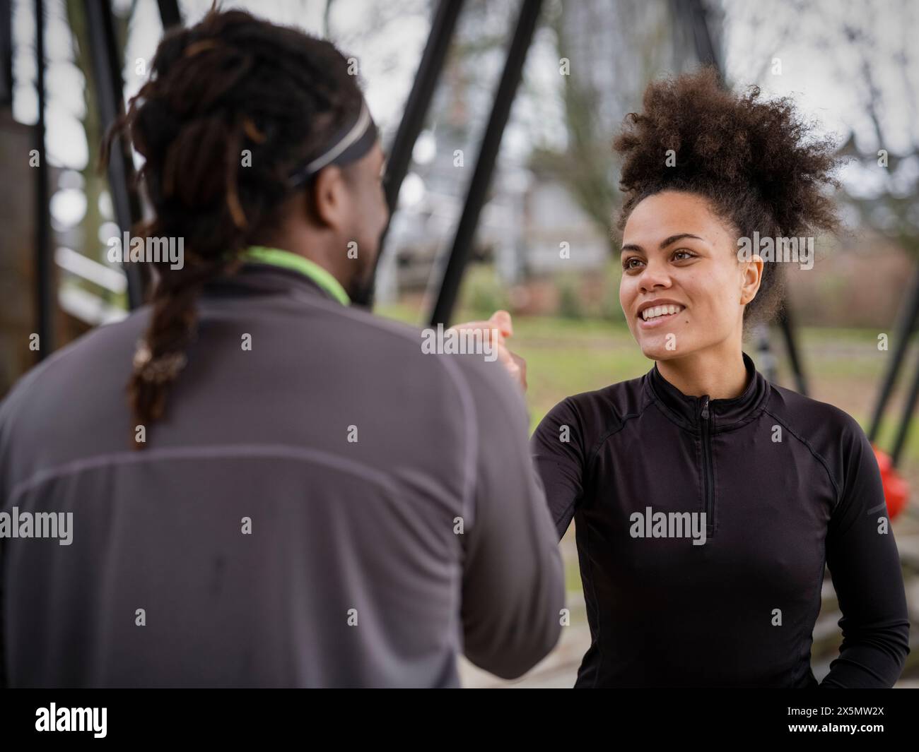 Uomo e donna sorridenti in abbigliamento sportivo braccio di lotta all'aperto Foto Stock