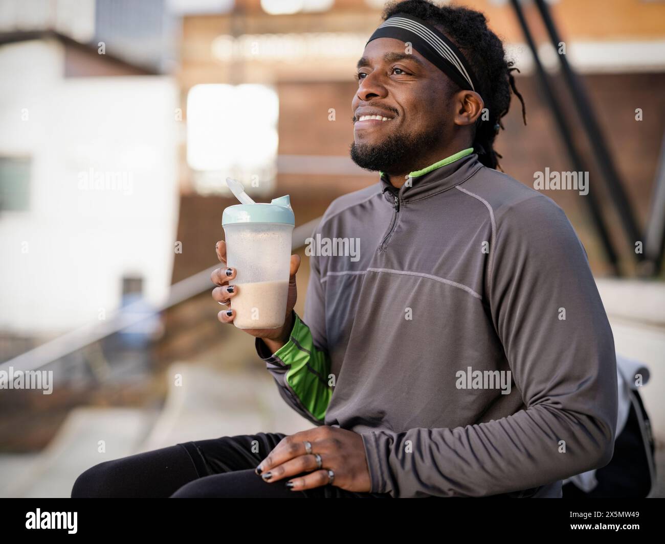 Uomo atletico sorridente con bevande proteiche all'aperto Foto Stock