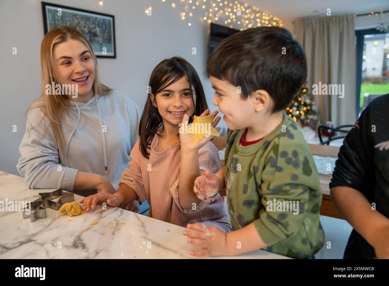 Mamma con bambini che preparano biscotti di Natale in cucina Foto Stock