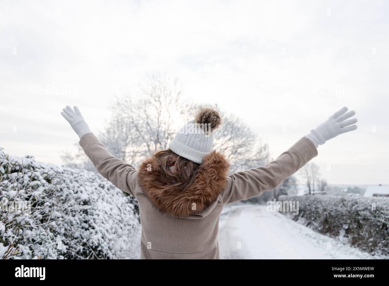 Vista posteriore della donna con le braccia sollevate nel paesaggio invernale Foto Stock