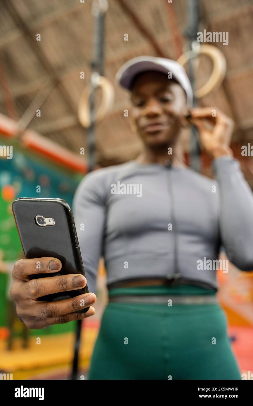 Donna con cuffie intrauricolari e smartphone in palestra Foto Stock