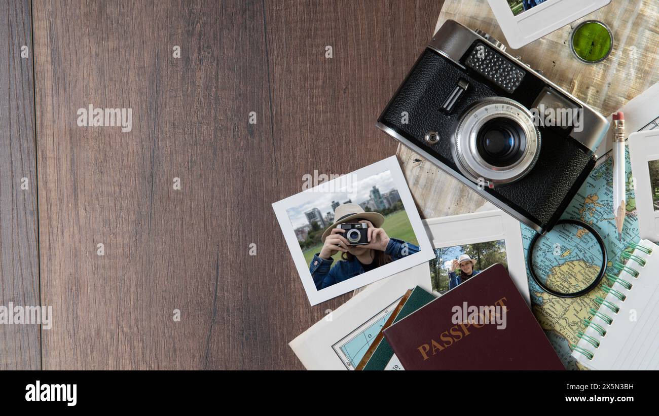 Vista dall'alto delle fotografie di una donna che scatta foto, passaporti, vecchia fotocamera, mappa e quaderno su un tavolo di legno scuro Foto Stock