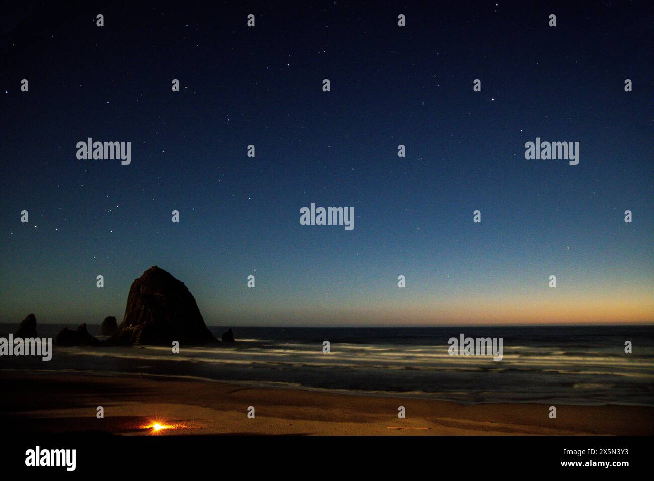 Stati Uniti, Oregon. Cannon Beach e Haystack Rock luci e stelle serali. Foto Stock