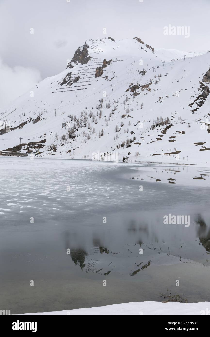 La Pointe du Lavachet, nella località sciistica alpina francese di Tignes, si riflette in una parte del lago ghiacciato che si sta sciogliendo all'inizio di maggio. Foto Stock