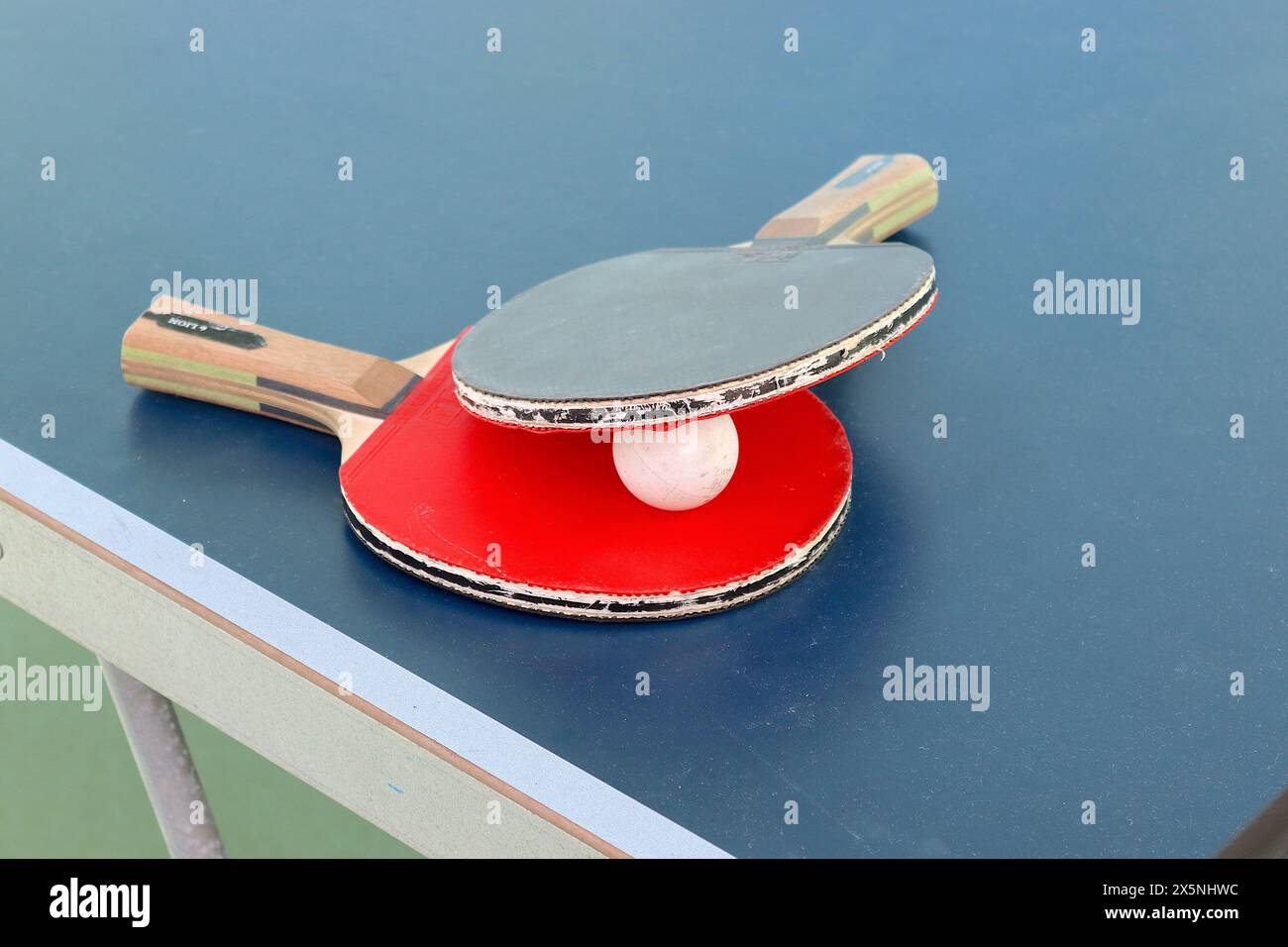 Palla e pipistrelli da ping-pong, lasciati sul tavolo da gioco dopo una partita competitiva tra amici che richiedono una reazione rapida e un'attenzione costante. Foto Stock