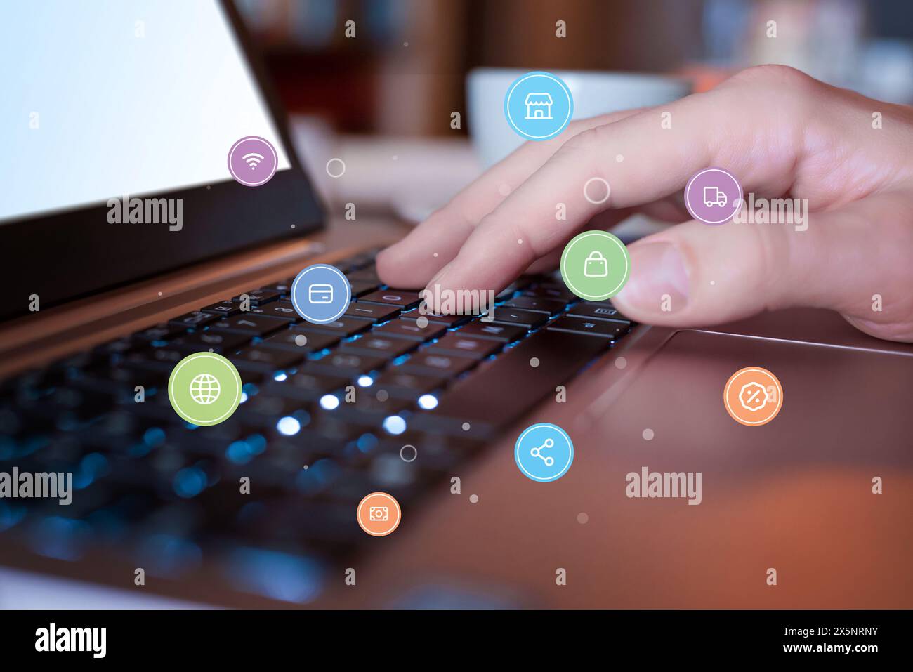 Shopping online con un computer portatile al bar. Le icone del concept shopping che volano in giro. Stile di vita moderno con comodità digitali e tempo libero Foto Stock