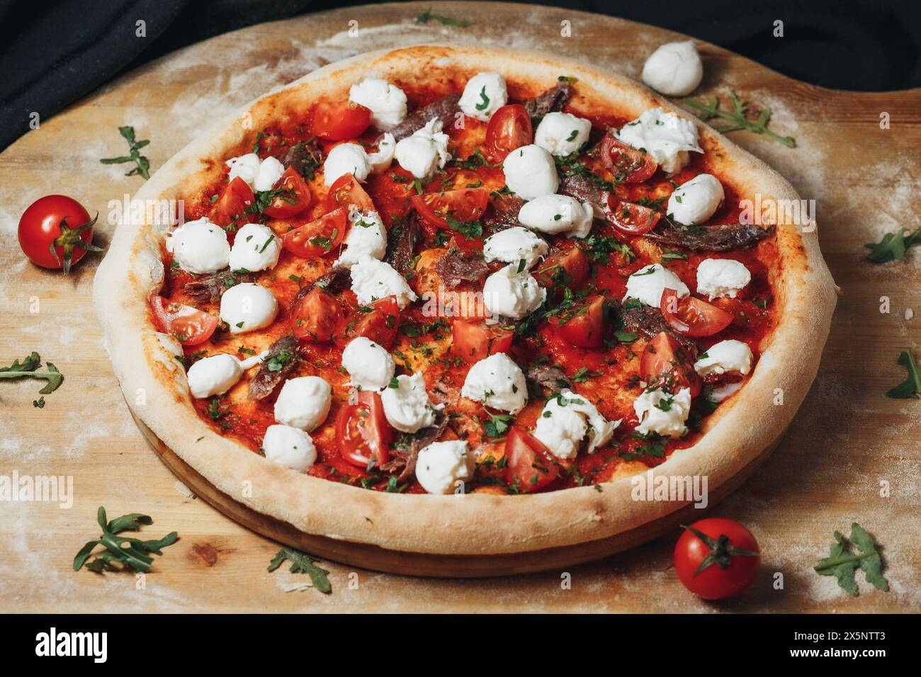 Pizza Margherita appena sfornata con pomodori ciliegini e mozzarella su tavola di legno Foto Stock