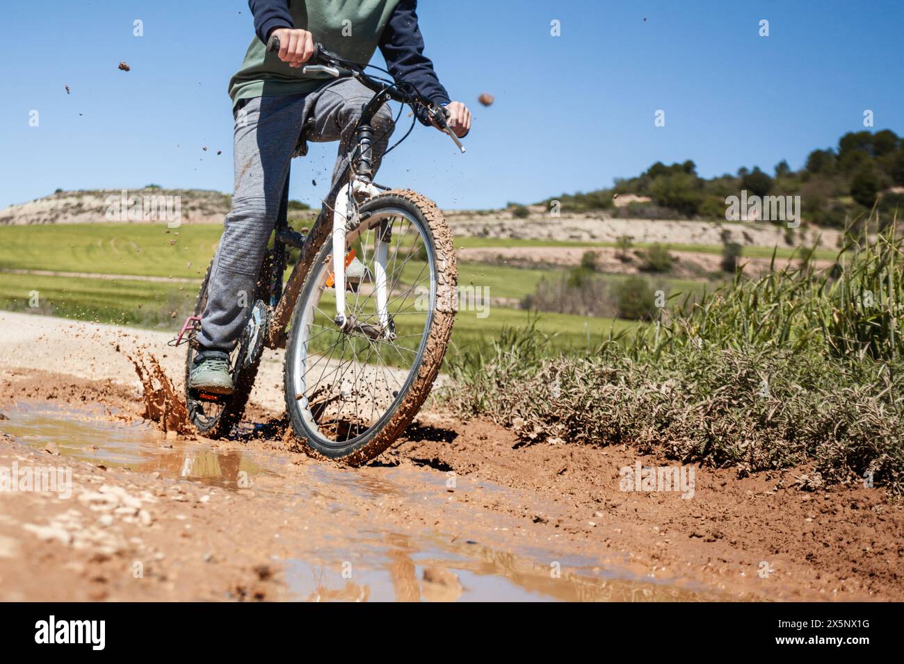 Un uomo sta andando in bicicletta su una strada fangosa. La bici è coperta di fango. La scena è avventurosa ed emozionante Foto Stock