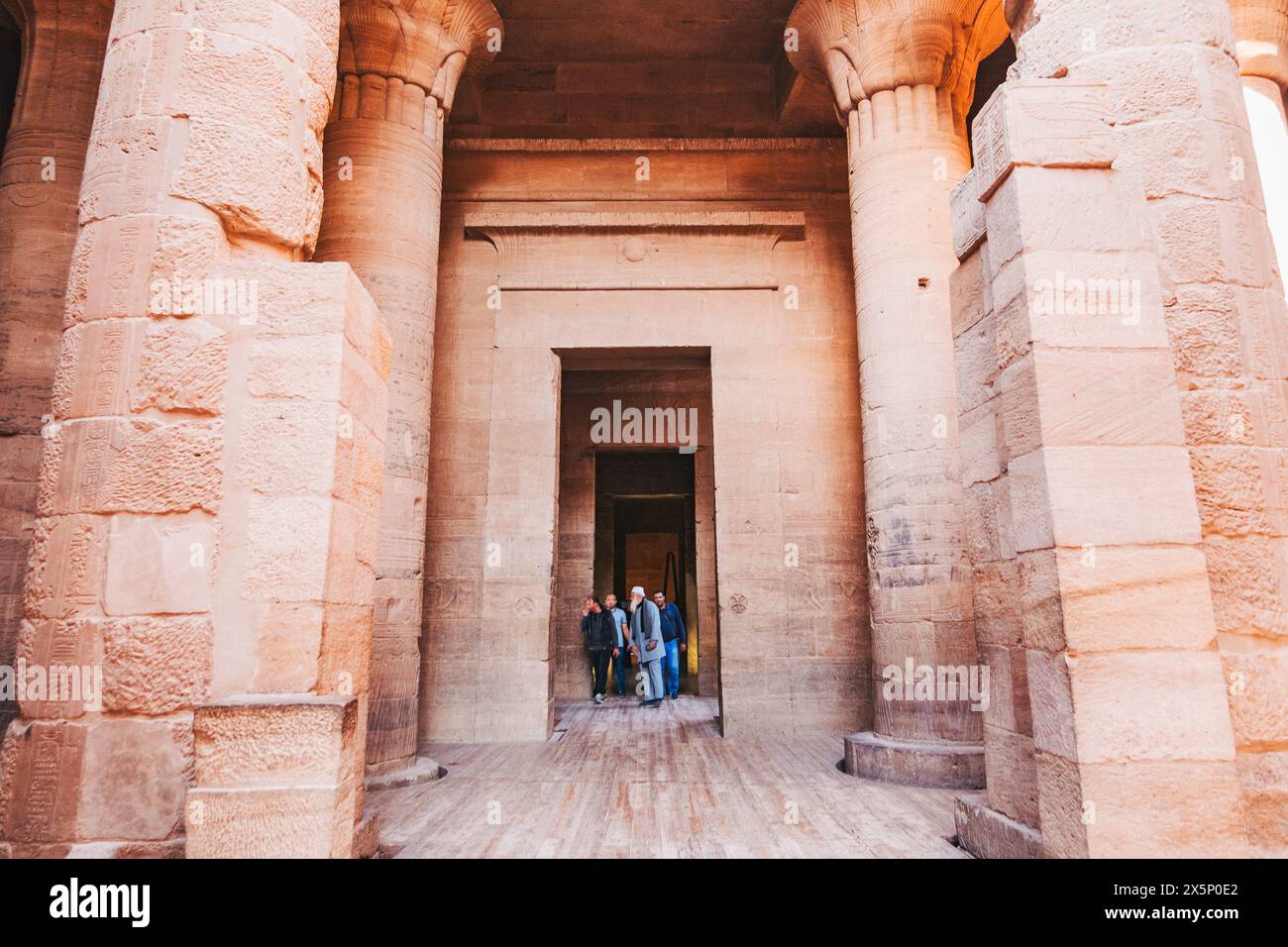 I turisti che visitano il complesso del tempio di file ad Assuan, in Egitto, camminano attraverso una grande porta Foto Stock