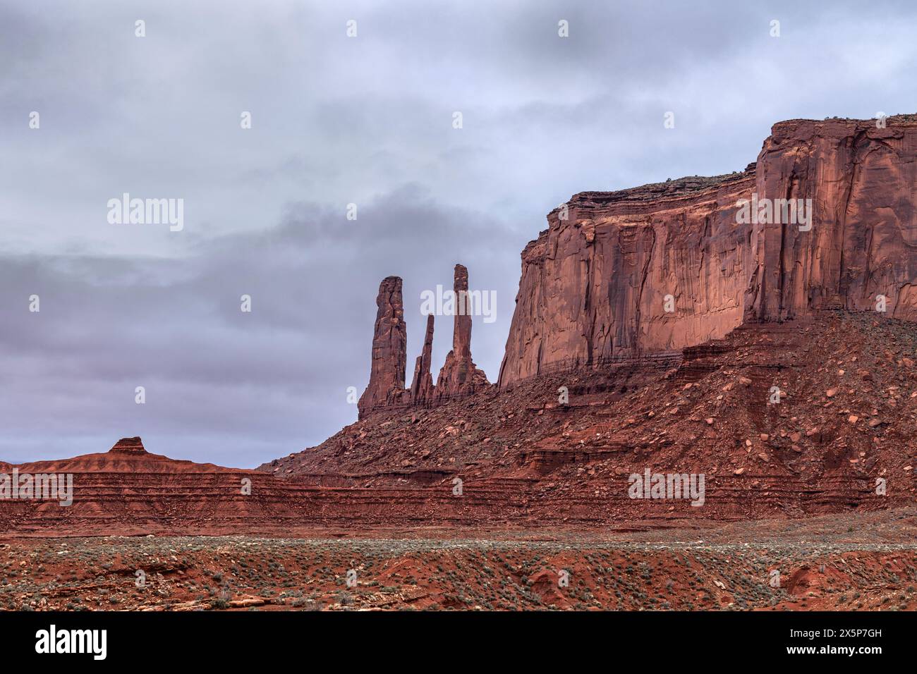 Famous Three Sisters nella Monument Valley è un residuo altamente eroso di una butte e sorge accanto a una lunga catena montuosa di arenaria, moenkopi e. Foto Stock