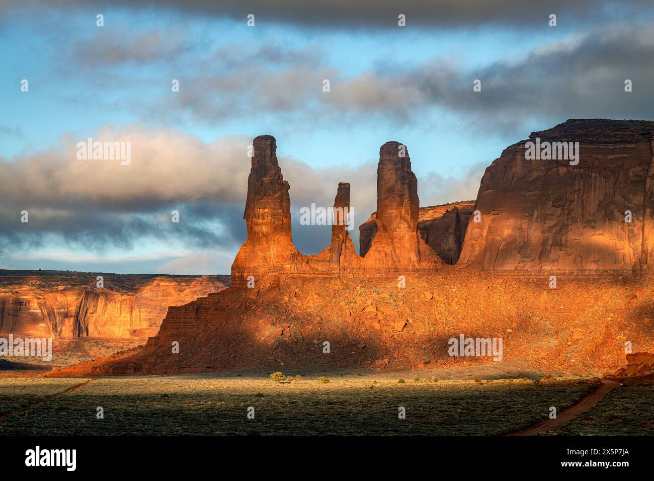 Un panorama della catena montuosa che ospita le famose guglie delle tre Sorelle nella Monument Valley, Arizona, sulla sinistra dell'immagine durante una nuvolosa e piovosa Foto Stock