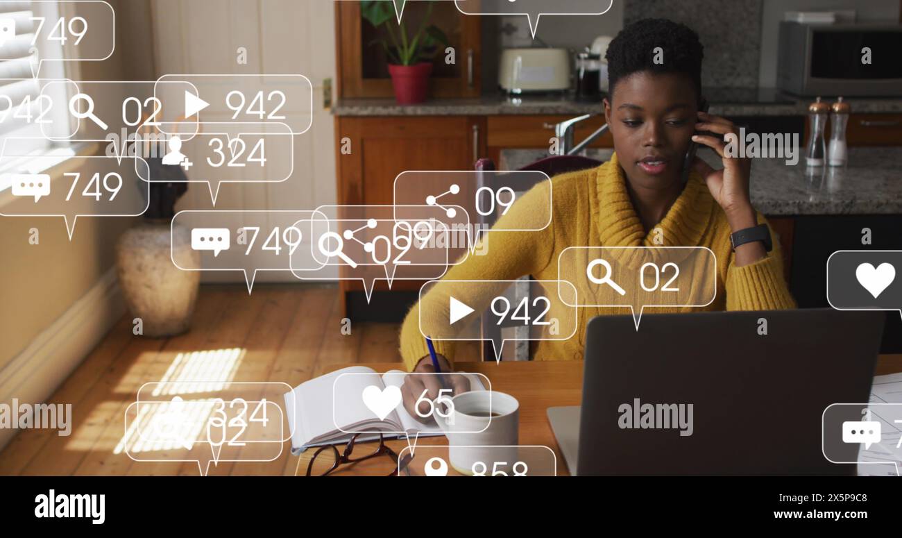 Una cuoca/cliente afroamericana sta parlando al telefono, utilizzando un computer portatile Foto Stock