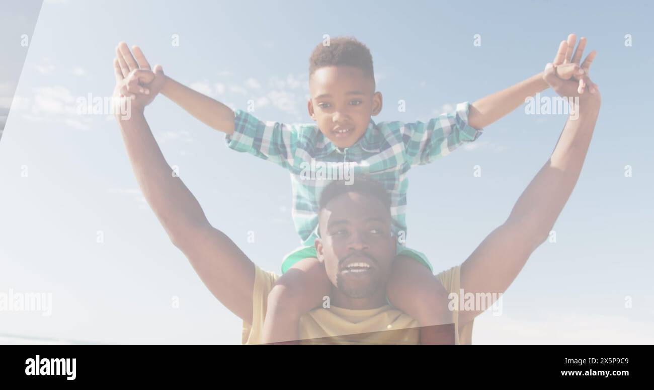 Padre afroamericano che solleva il figlio sulle spalle, entrambi sorridenti sotto il cielo limpido Foto Stock