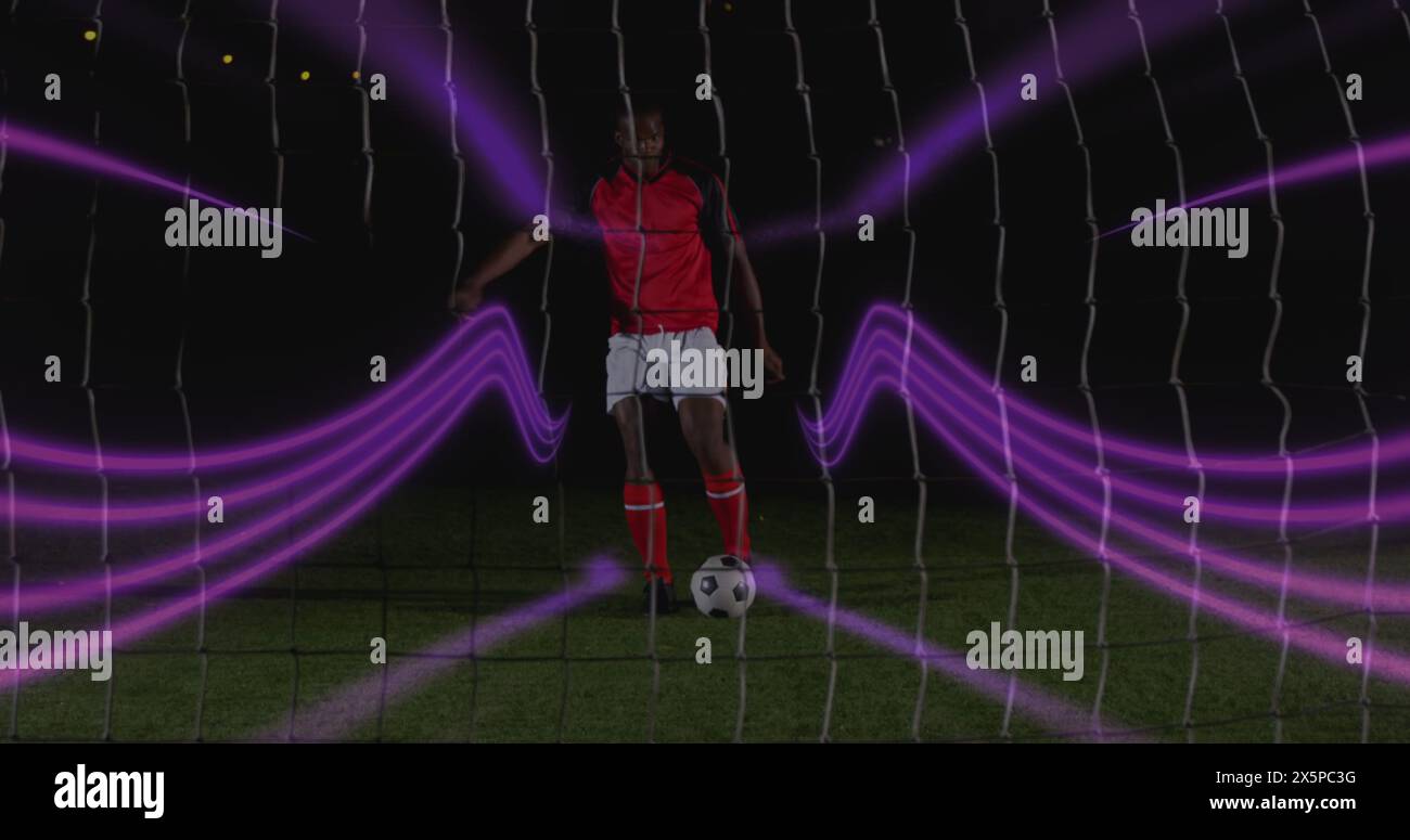 Immagine di sentieri luminosi colorati sopra un calciatore afroamericano che prende un calcio di rigore Foto Stock