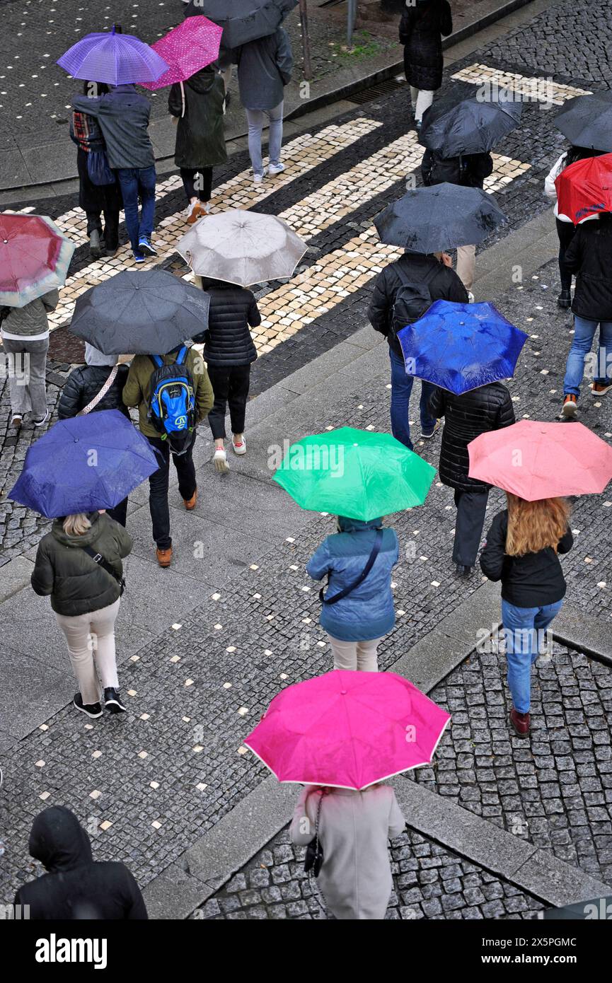 Persone che attraversano una strada con ombrelli colorati in una giornata di pioggia a Porto, Portogallo, Europa Foto Stock