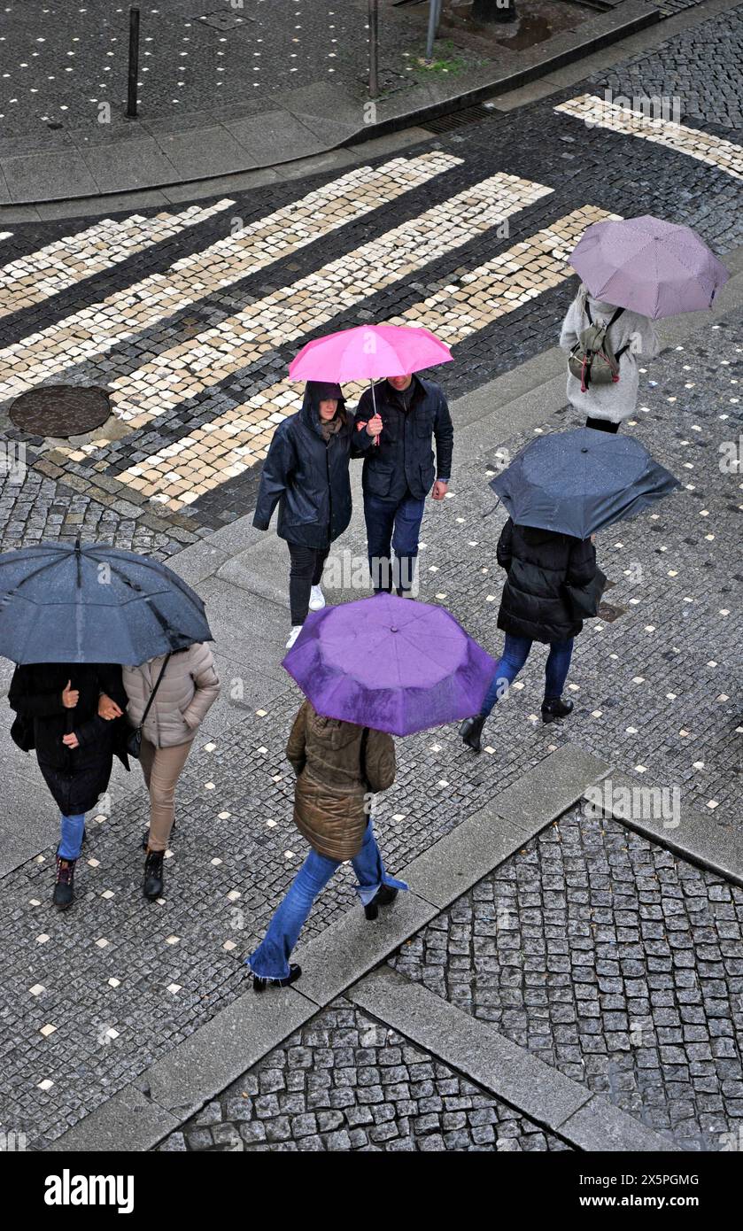 Persone che attraversano una strada con ombrelli colorati in una giornata di pioggia a Porto, Portogallo, Europa Foto Stock