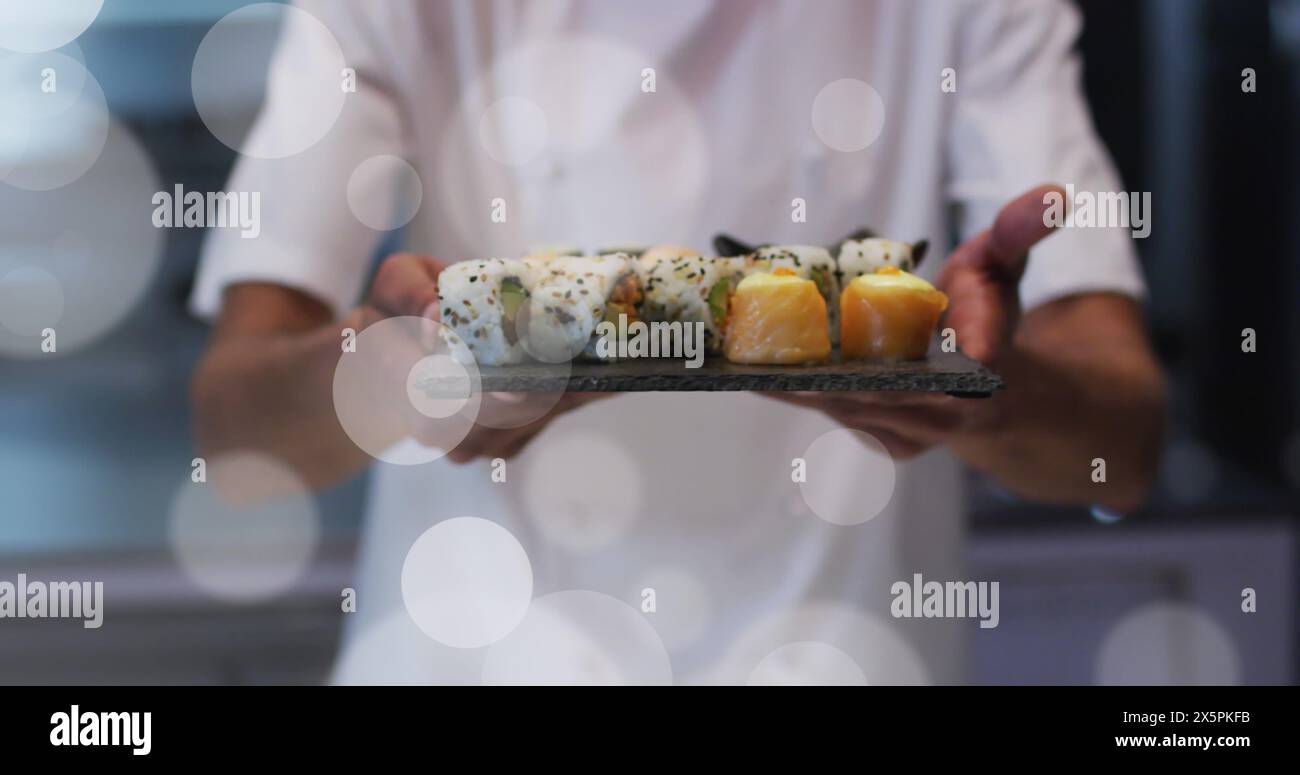 Immagine di faretti bianchi sullo chef maschile che serve sushi Foto Stock