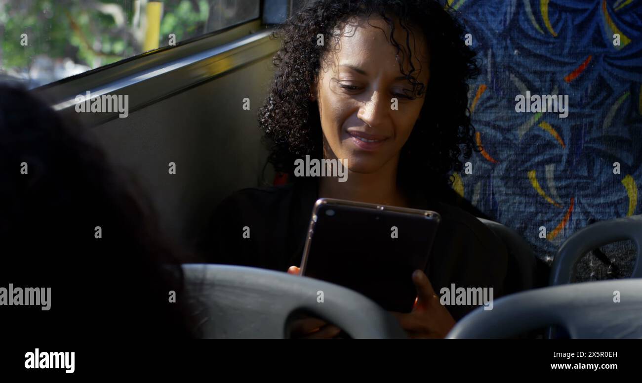 Donna birazziale che tiene un tablet sull'autobus, guarda lo schermo Foto Stock