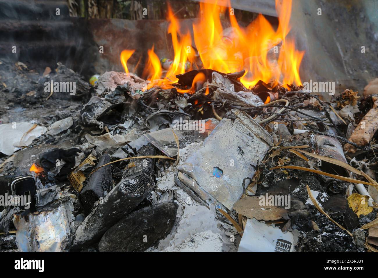 Filippine e problema di inquinamento dei rifiuti: Elettronica bruciata tra i rifiuti domestici: IPhone, batteria al litio power Bank, cavi, caricabatterie, scarico tecnologico Foto Stock