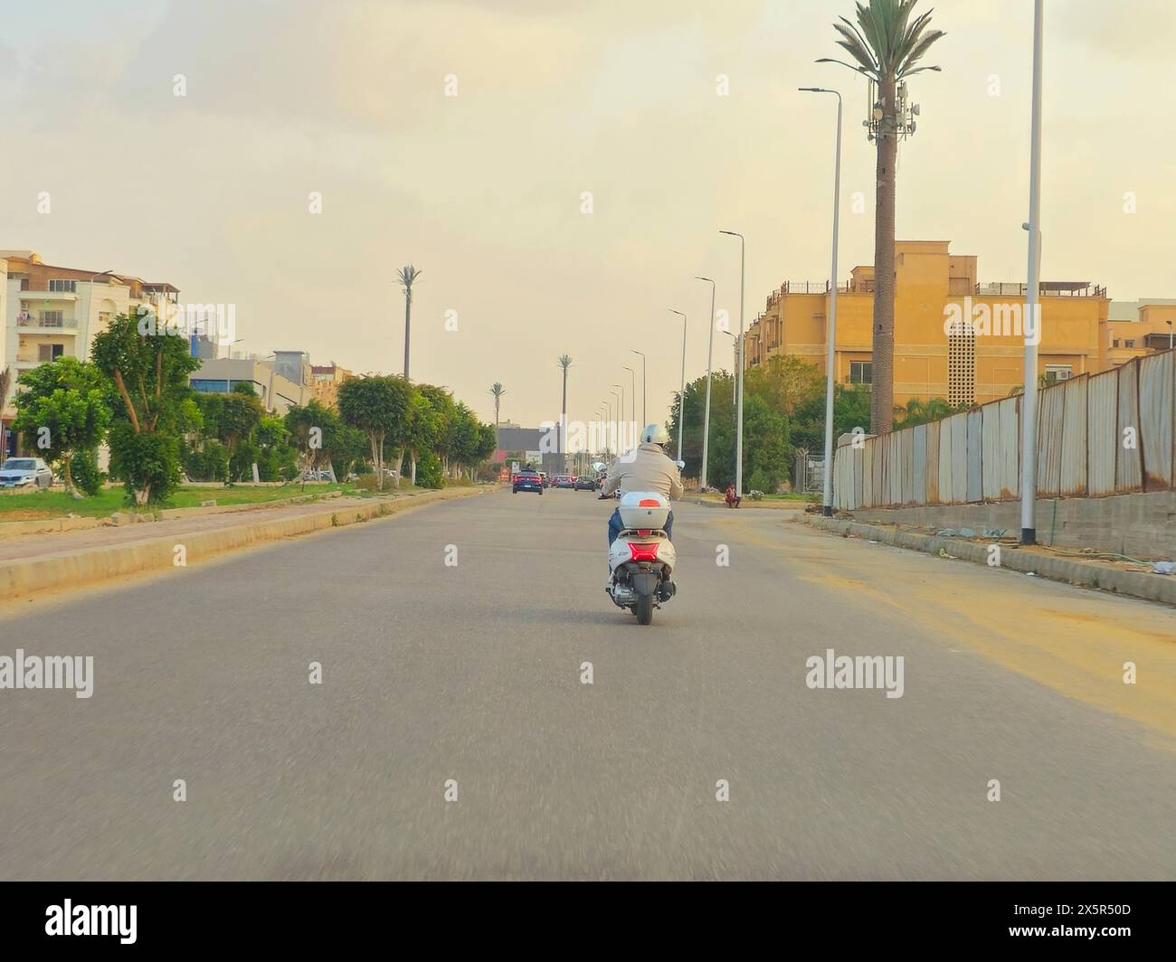 Cairo, Egitto, marzo 29 2024: Un uomo alla guida di uno scooter, uno scooter è una moto con un sottoscocca o telaio passante, un sedile, una trasmissione Foto Stock