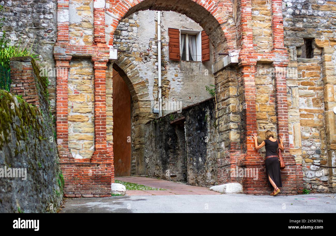 La donna appoggiata su porta Rugo nel centro di Belluno in Italia Foto Stock