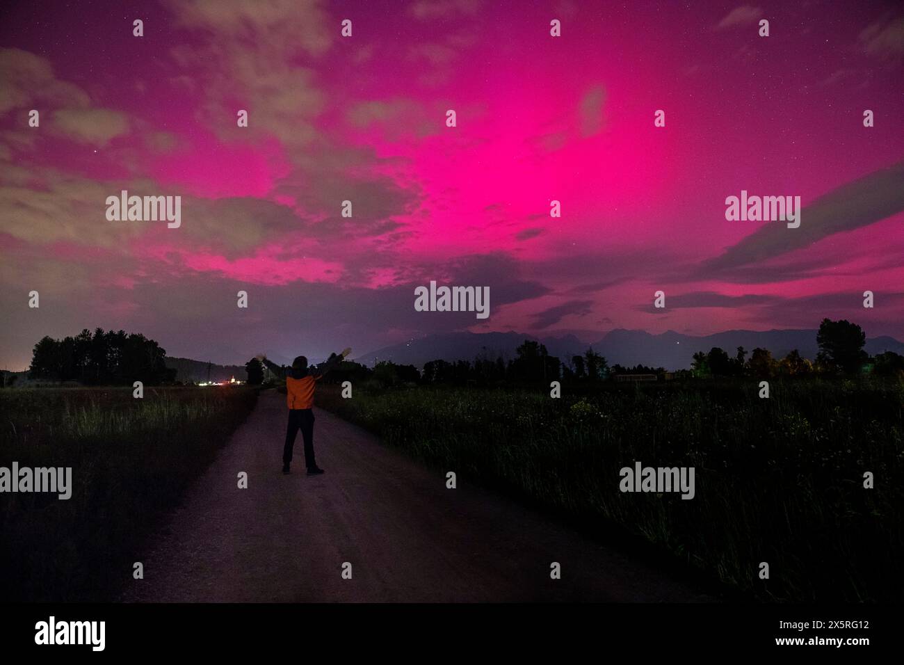 Ragazzo locale che guarda la spettacolare luce boreale, l'aurora boreale che illuminava il cielo notturno vicino alla capitale Lubiana in Slovenia Foto Stock